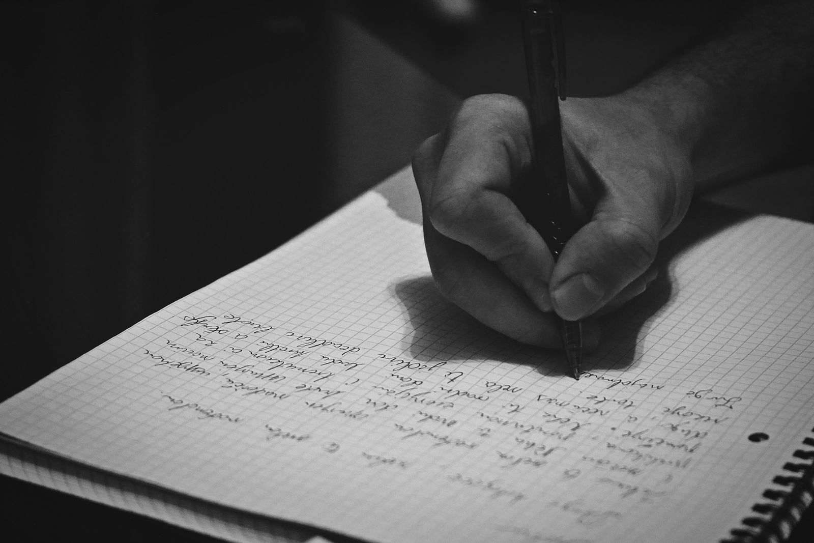 A hand writing in a notebook with a pen.