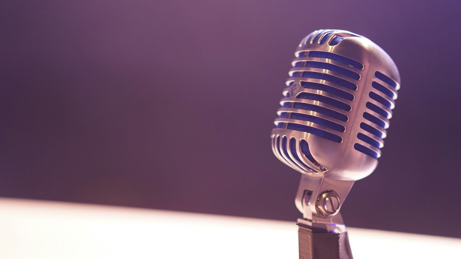 A vintage microphone against a purple background.